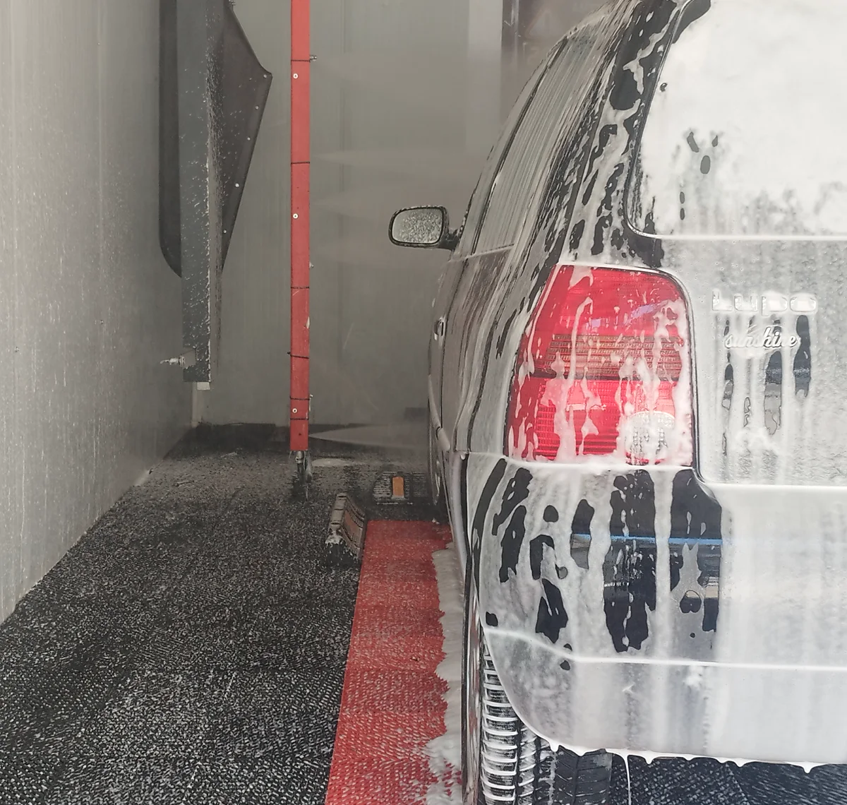 Devreye alınmış ZetaWash yıkama tesisi, köpük fazındaki araç ve kırmızı yıkama kolu